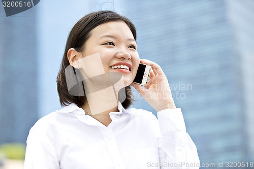 Image of Asian young female executive talking on smart phone