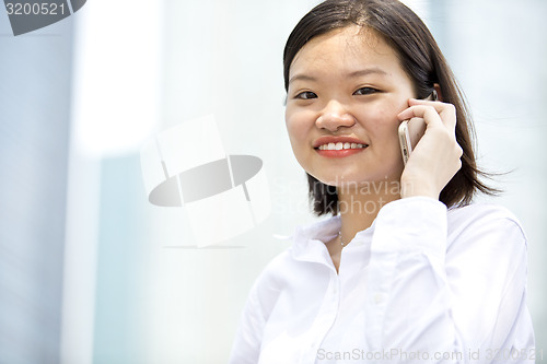 Image of Asian young female executive talking on smart phone