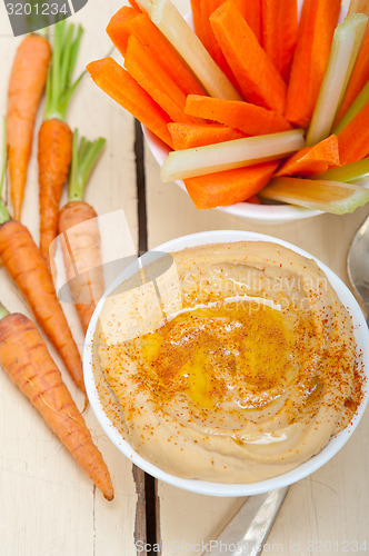 Image of fresh hummus dip with raw carrot and celery 