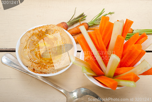 Image of fresh hummus dip with raw carrot and celery 