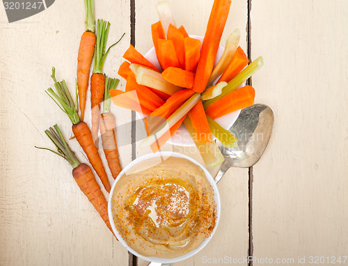 Image of fresh hummus dip with raw carrot and celery 