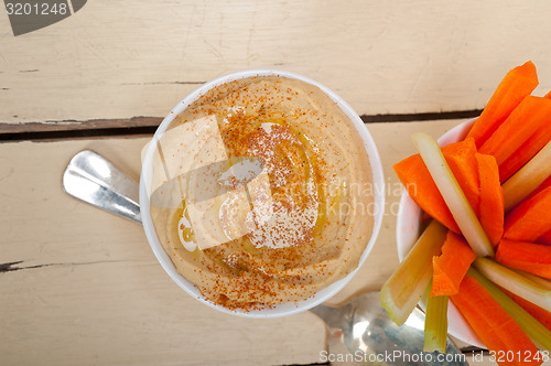 Image of fresh hummus dip with raw carrot and celery 