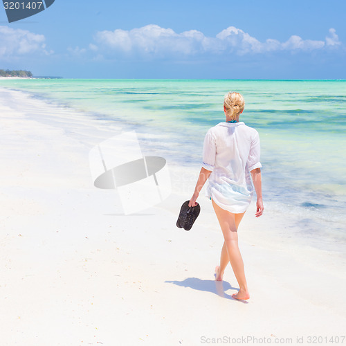 Image of Woman running on the beach in sunset.