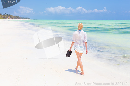 Image of Woman running on the beach in sunset.