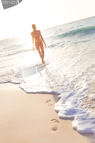 Image of Woman running on the beach in sunset.