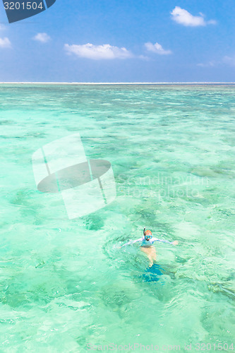 Image of woman snorkeling in turquoise blue sea.