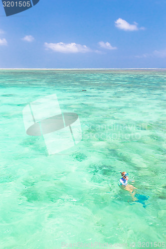 Image of woman snorkeling in turquoise blue sea.