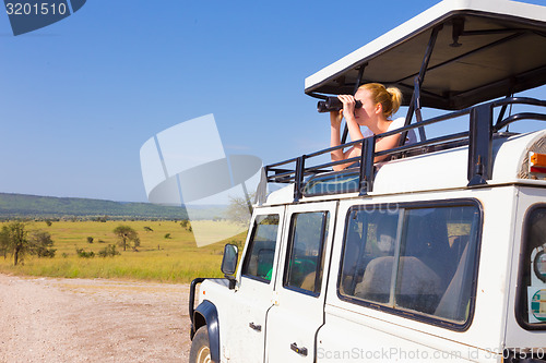 Image of Woman on safari looking through binoculars.