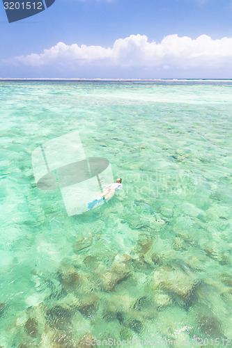 Image of woman snorkeling in turquoise blue sea.