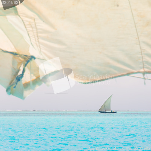 Image of Traditional wooden sailboat sailing on horizon.