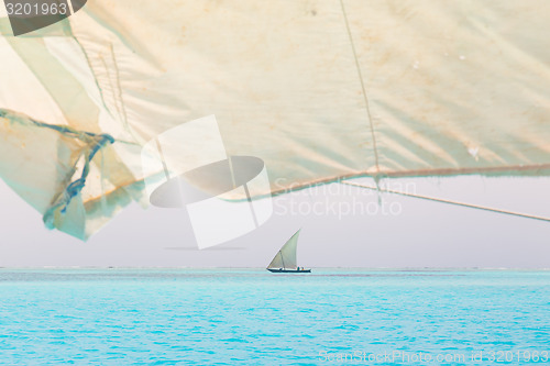 Image of Traditional wooden sailboat sailing on horizon.