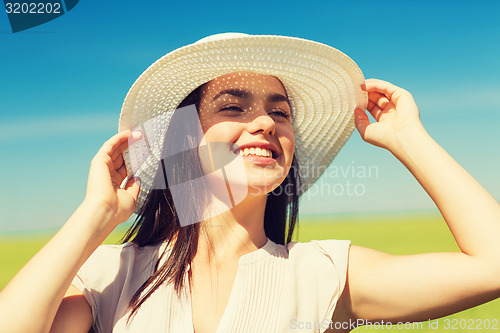 Image of smiling young woman in straw hat outdoors