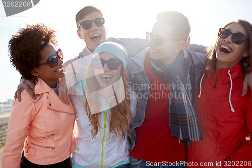 Image of smiling friends in sunglasses laughing on street