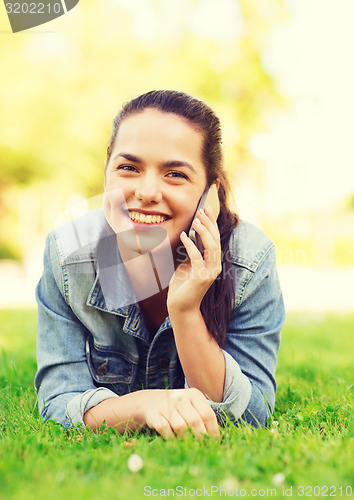 Image of smiling young girl with smartphone lying on grass