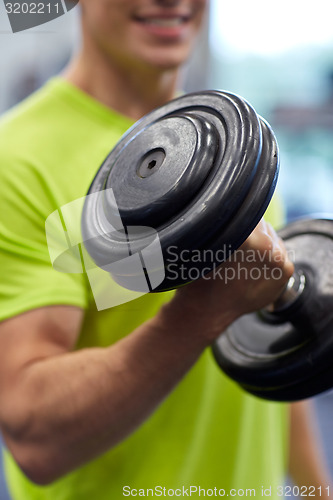 Image of close up of smiling man with dumbbell in gym