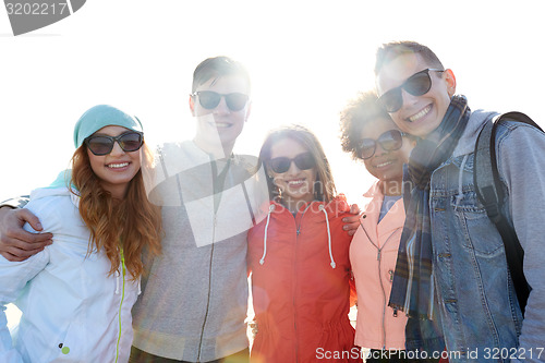 Image of happy teenage friends in shades hugging on street