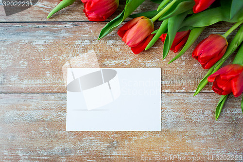 Image of close up of red tulips and blank paper or letter