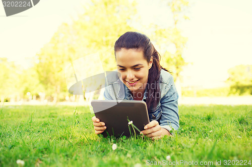 Image of smiling young girl tablet pc lying on grass