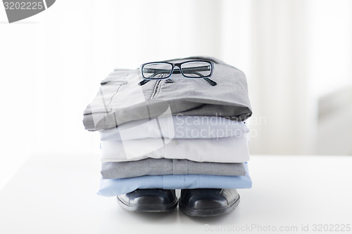 Image of close up of folded male shirts and shoes on table