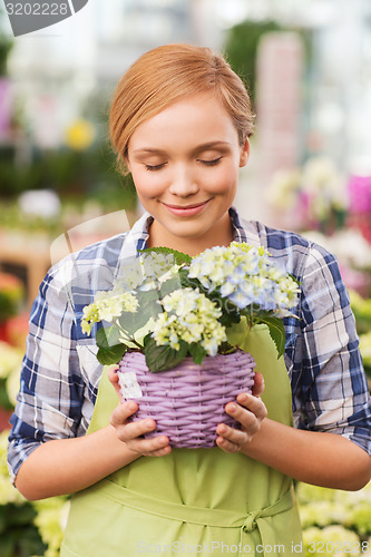 Image of happy woman smelling flowers in greenhouse