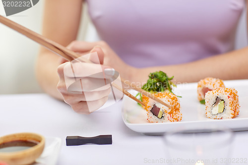 Image of close up of woman eating sushi at restaurant