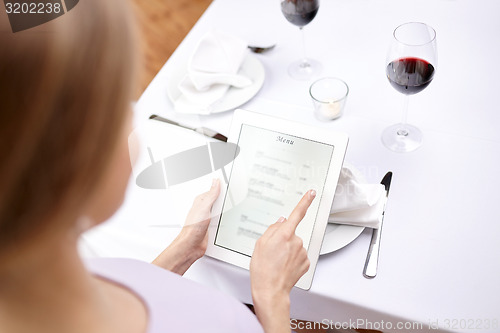 Image of close up of woman with tablet pc at restaurant