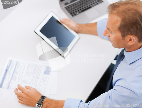 Image of businessman with tablet pc and papers in office