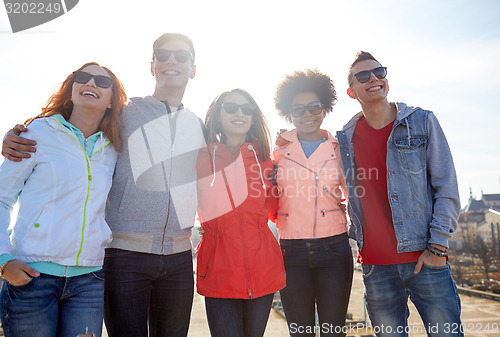 Image of happy teenage friends in shades hugging on street