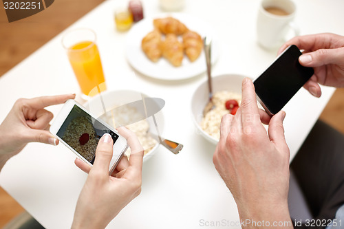 Image of close up of couple with smartphones at breakfast