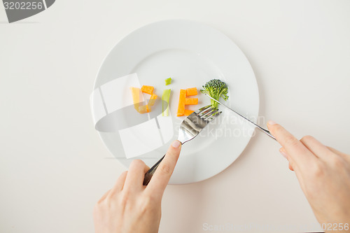 Image of close up of woman hands eating vegetables