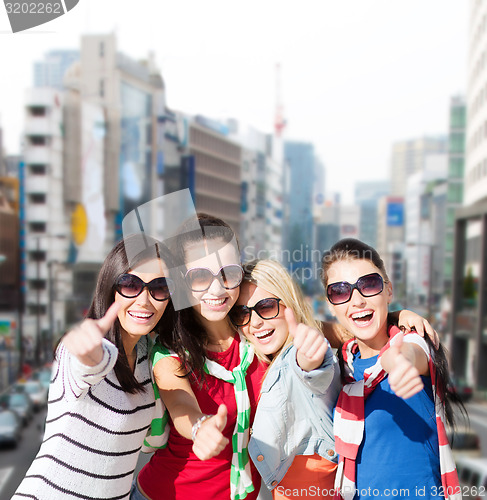 Image of happy teenage girls showing thumbs up at city
