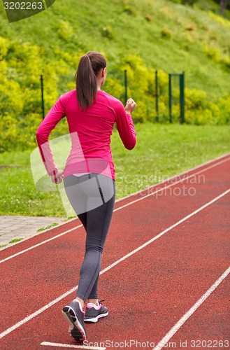 Image of woman running on track outdoors from back