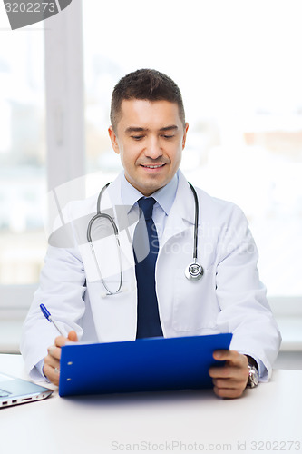 Image of happy doctor with clipboard in office