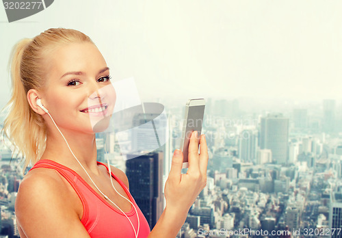 Image of smiling sporty woman with smartphone and earphones