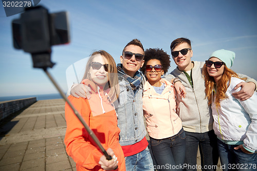 Image of smiling friends taking selfie with smartphone