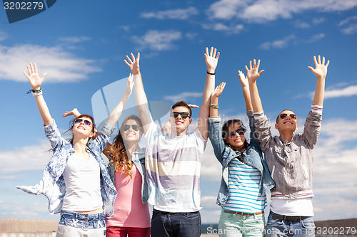 Image of group of smiling teenagers holding hands up