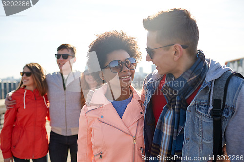 Image of happy teenage friends in shades talking on street