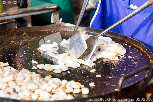 Image of close up of cook frying meat at street market
