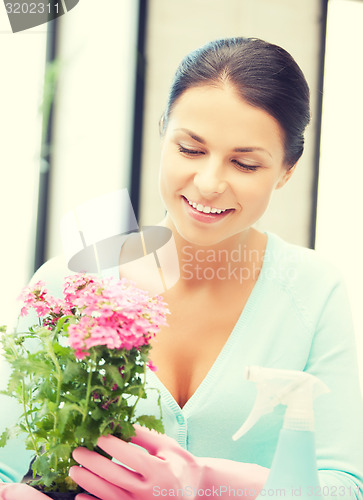 Image of woman holding pot with flower and spray bottle