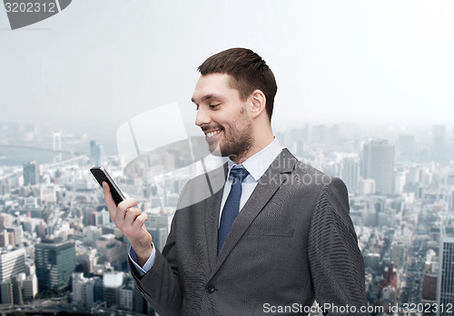 Image of young smiling businessman with smartphone