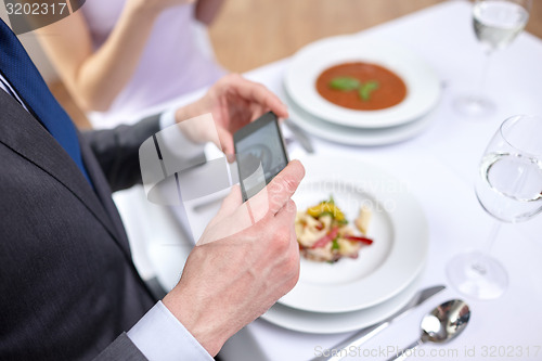 Image of close up of couple with smartphones at restaurant