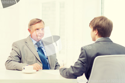 Image of older man and young man signing papers in office