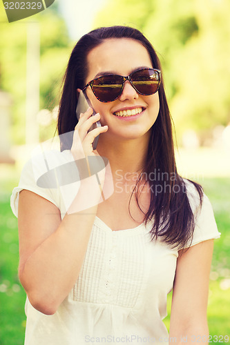 Image of smiling young girl with smartphone outdoors