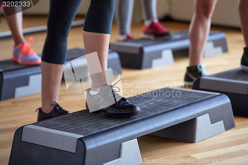 Image of close up of women exercising with steppers in gym