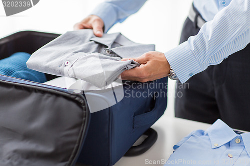 Image of businessman packing clothes into travel bag