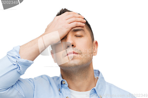 Image of unhappy man with closed eyes touching his forehead