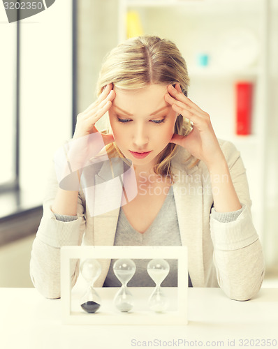 Image of tired woman behind the table with hourgalss