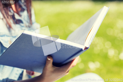 Image of close up of young girl with book in park