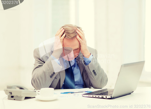 Image of upset older businessman with laptop and telephone