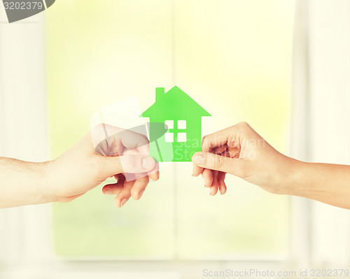 Image of couple hands holding green house